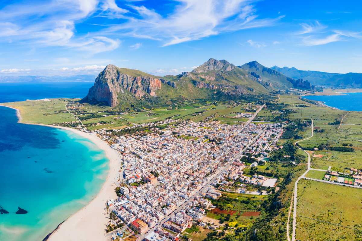 Veduta panoramica del lungomare di San Vito Lo Capo con spiaggia bianca, mare turchese e monte Monaco sullo sfondo, atmosfera rilassata e luminosa