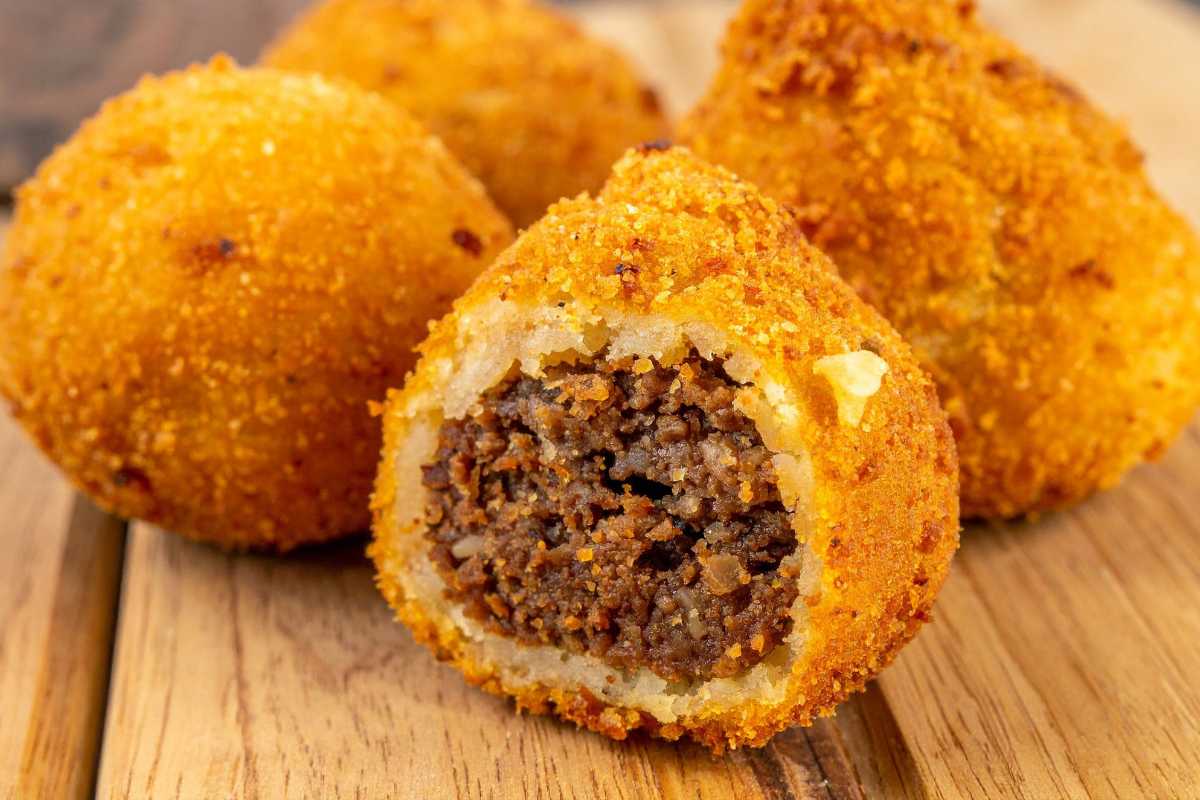Scorcio di un mercato alimentare all’aperto a San Vito Lo Capo, con banchi di pesce fresco, spezie, pane e street food, clienti che assaggiano panelle e arancine