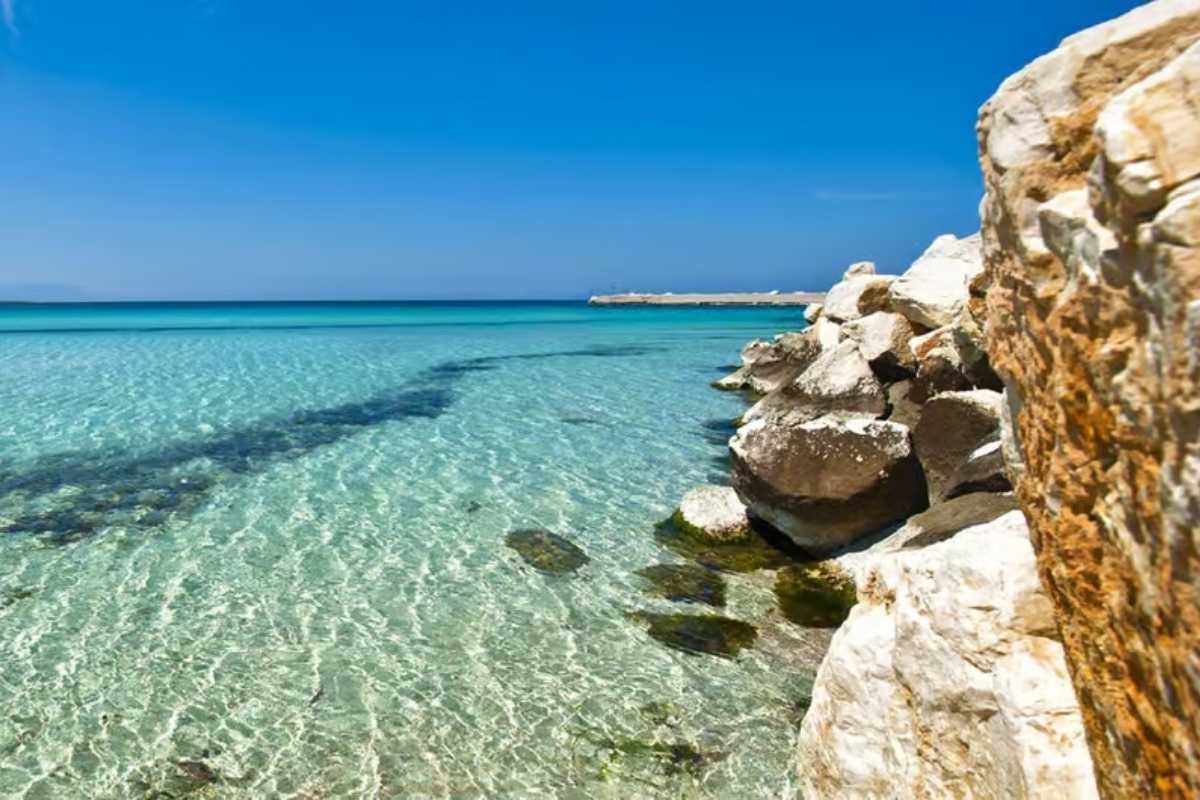 Scorcio panoramico dalla costa della Riserva dello Zingaro verso San Vito Lo Capo, sentiero costiero con mare turchese e vegetazione mediterranea, luce calda del pomeriggio